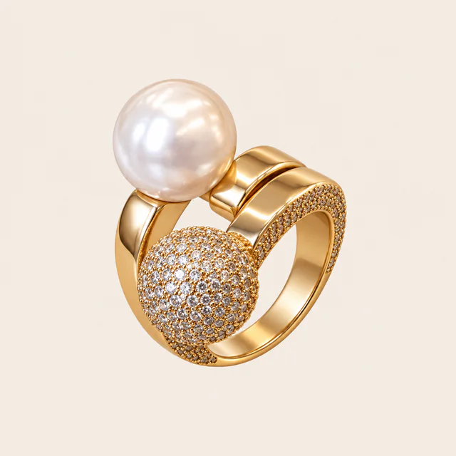 Anel dourado com pérola branca e detalhe arredondado cravejado, em vista de três quartos.