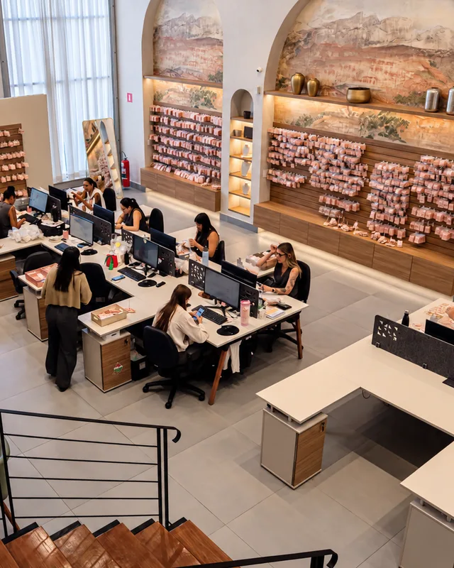 Showroom da Pedra Bruta em Limeira visto do alto da escada: nichos em arco com semijoias expostas e mesas de atendimento.