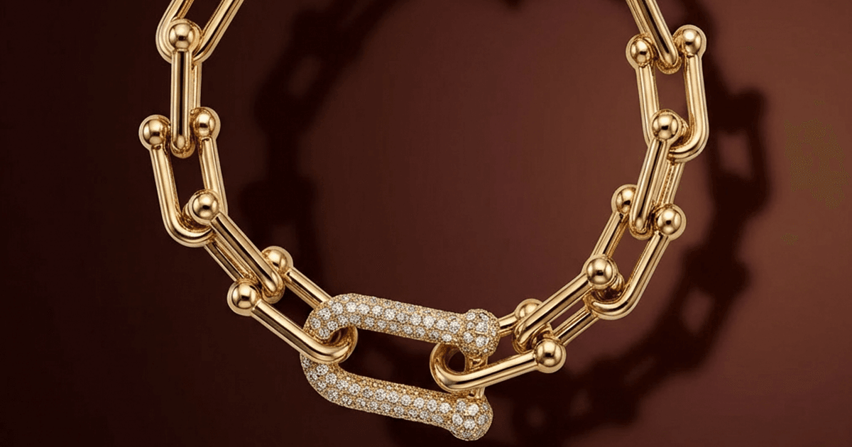 Fotografia profissional de um colar de elos banhado a ouro com fecho cravejado. Imagem de alta qualidade demonstrando o padrão visual do aplicativo JoiasLab para o catálogo da Pedra Bruta Semijoias.